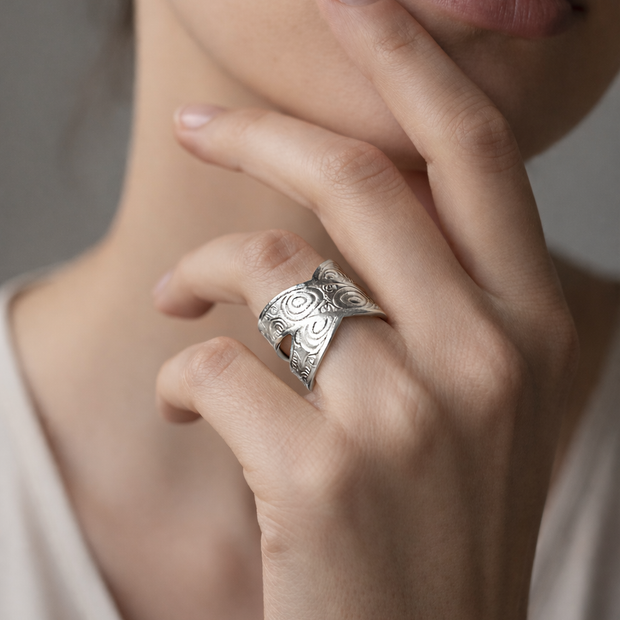 Anillo plateado cruzado con motivos circulares