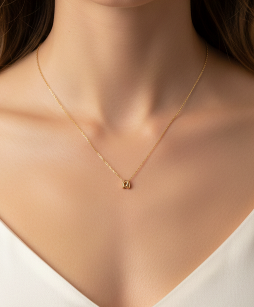 Mujer usando collar dorado con colgante de letra A Namare