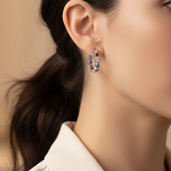 Mujer usando pendientes de aro plateados con circonitas de colores Namare