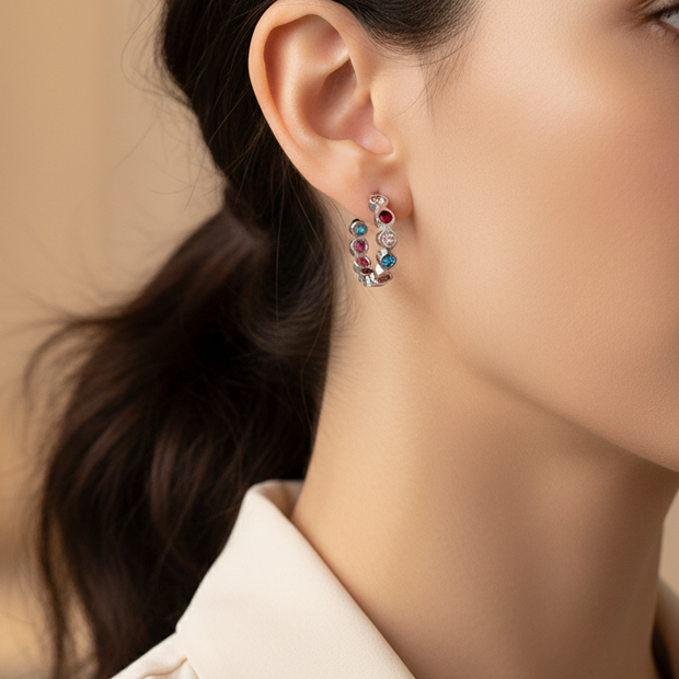 Mujer usando pendientes de aro plateados con circonitas de colores Namare