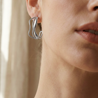 Pendientes de aros plateados con diseño ondulado y triple línea