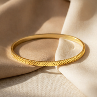 Pulsera rígida dorada tipo brazalete con borde dentado y corazones