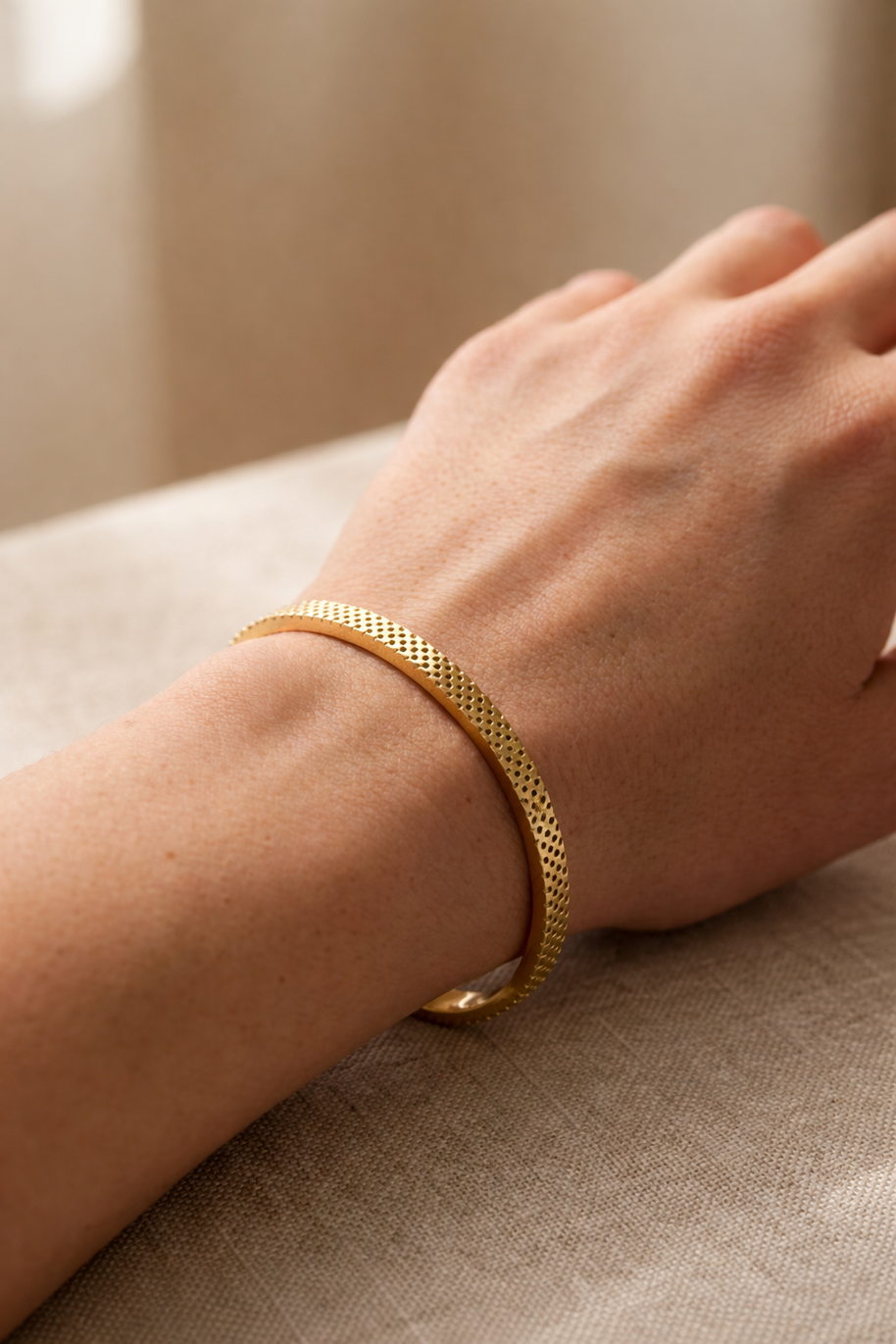 Pulsera rígida dorada tipo brazalete con borde dentado y corazones