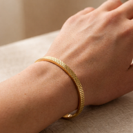 Pulsera rígida dorada tipo brazalete con borde dentado y corazones