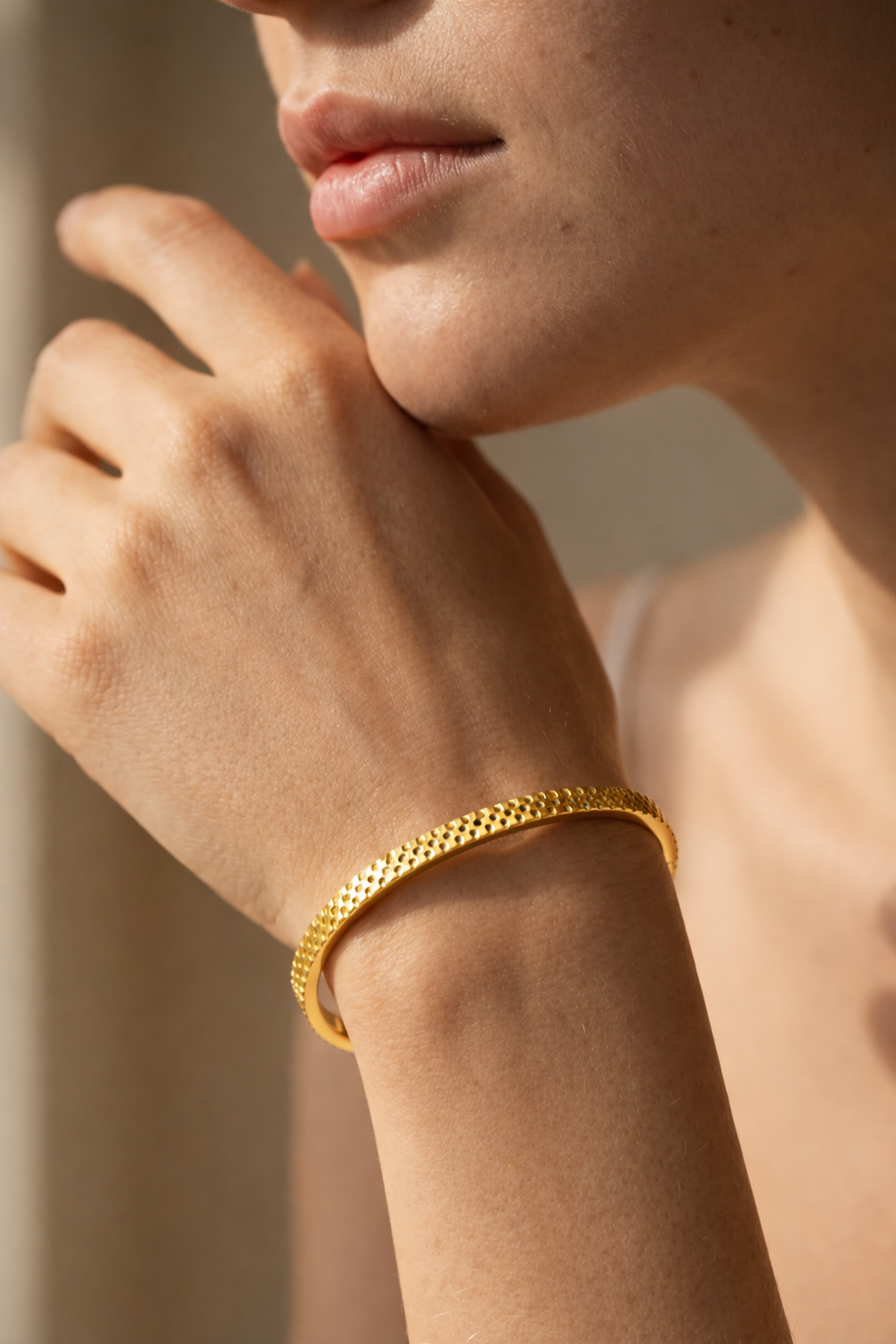 Pulsera rígida dorada tipo brazalete con borde dentado y corazones