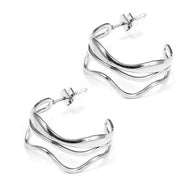 Pendientes de aros plateados con diseño ondulado y triple línea.
