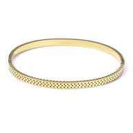 Pulsera rígida dorada tipo brazalete con borde dentado y corazones.
